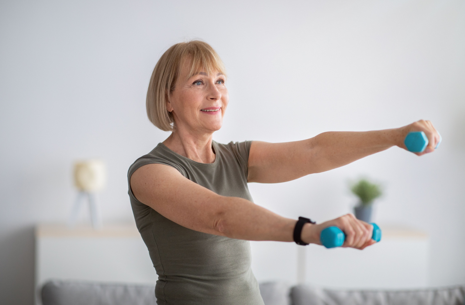 A smiling senior woman exercising with dumbbells.