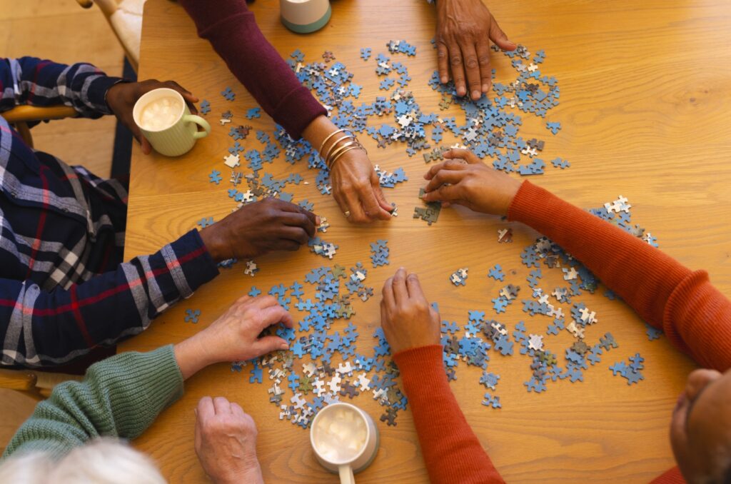 A close-up top view of a group of older adults doing a puzzle together.