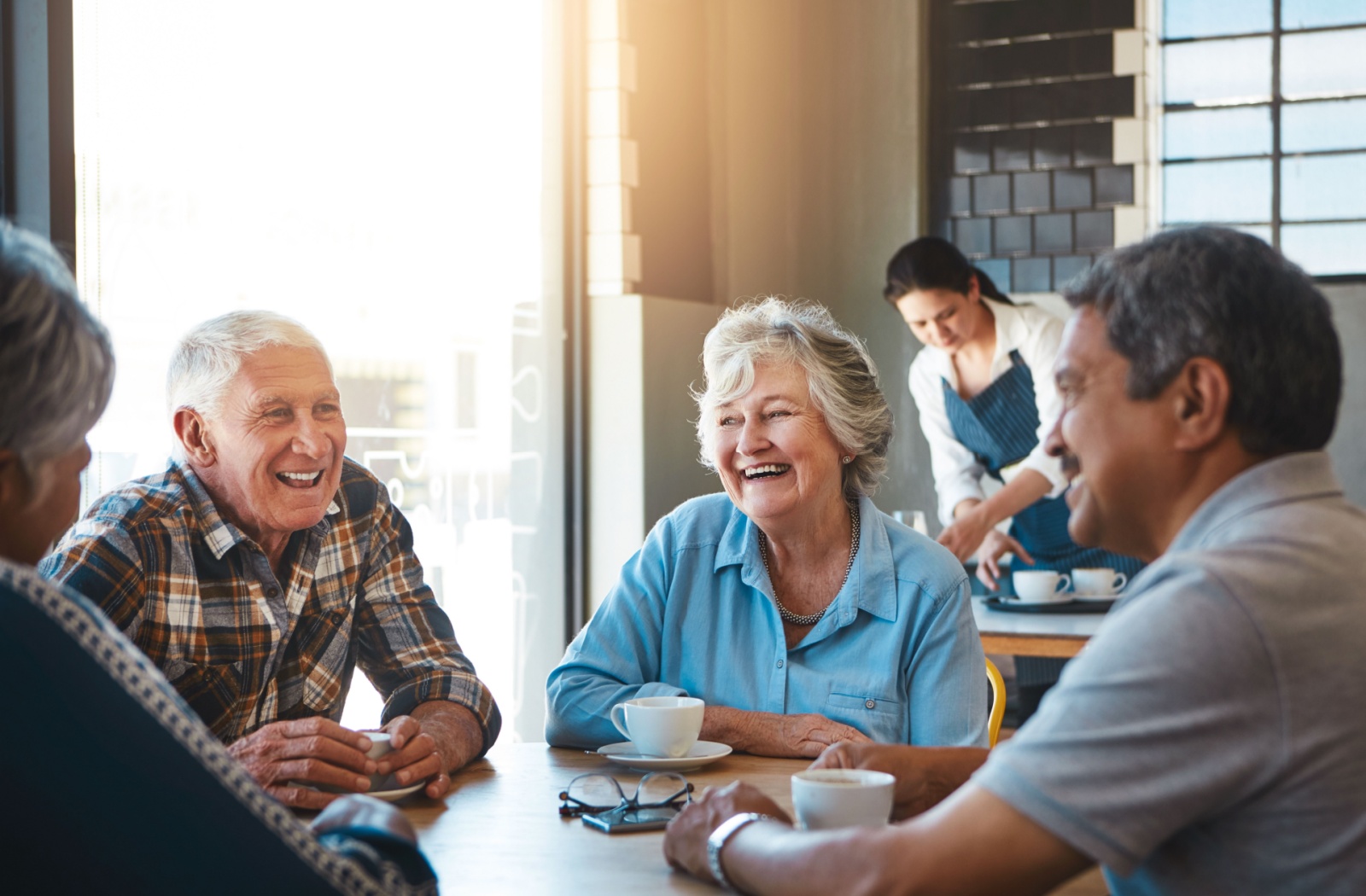 A group of senior friends share conversation and coffee in a relaxing cafe.