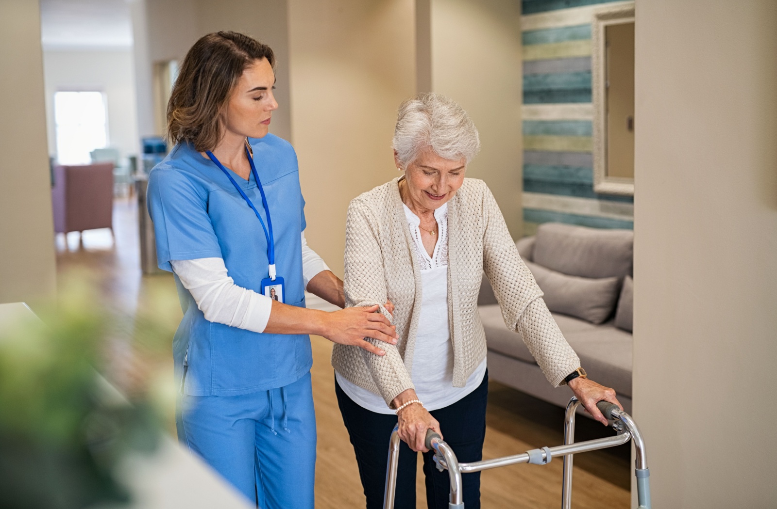 A nurse provides some mobility assistance to a senior using a walker in assisted living