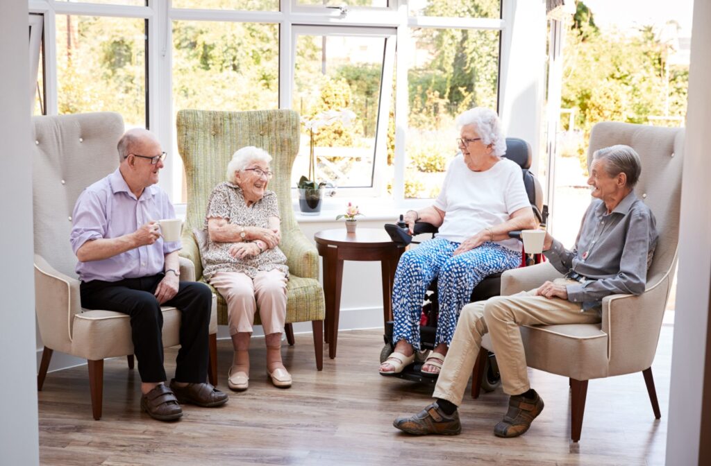Four seniors socialize in a communal space of their assisted living homes, enjoying each other’s company