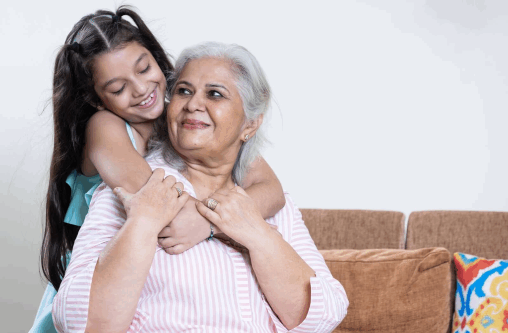 A caring small child embraces a smiling senior as they visit their grandparent in assisted living.