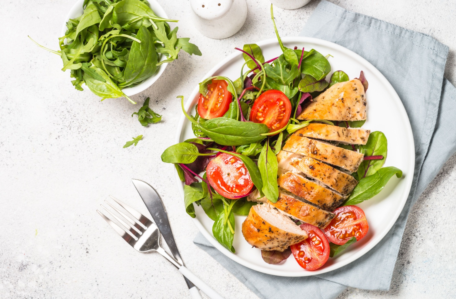 A colorful plate with vibrant greens, sliced tomatoes, and sliced chicken breast.