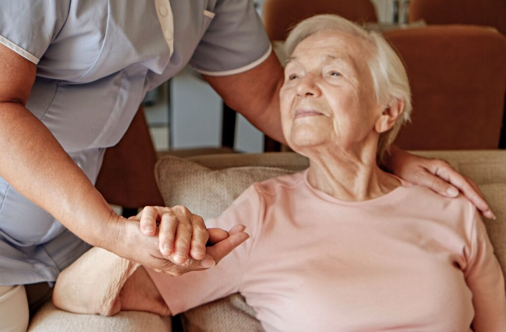 A caregiver offers support to an older adult in a cozy senior living space.