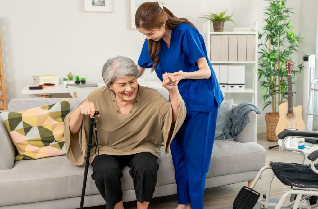 a caregiver helping a senior stand up from the sofa