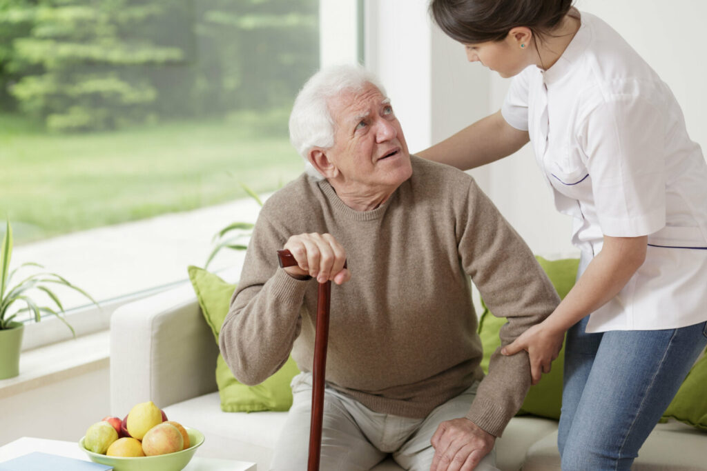 A nurse helping a senior man suffering from Parkinson's disease.
