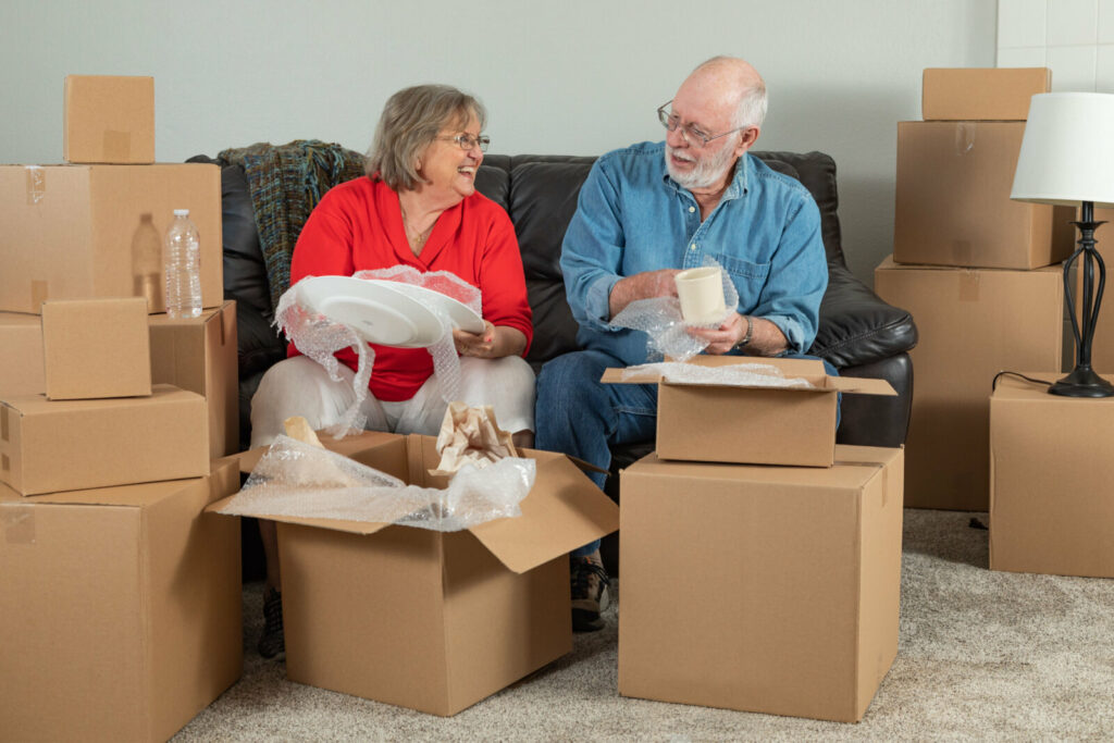 A senior couple unboxing cardboard boxes at their new smaller house.