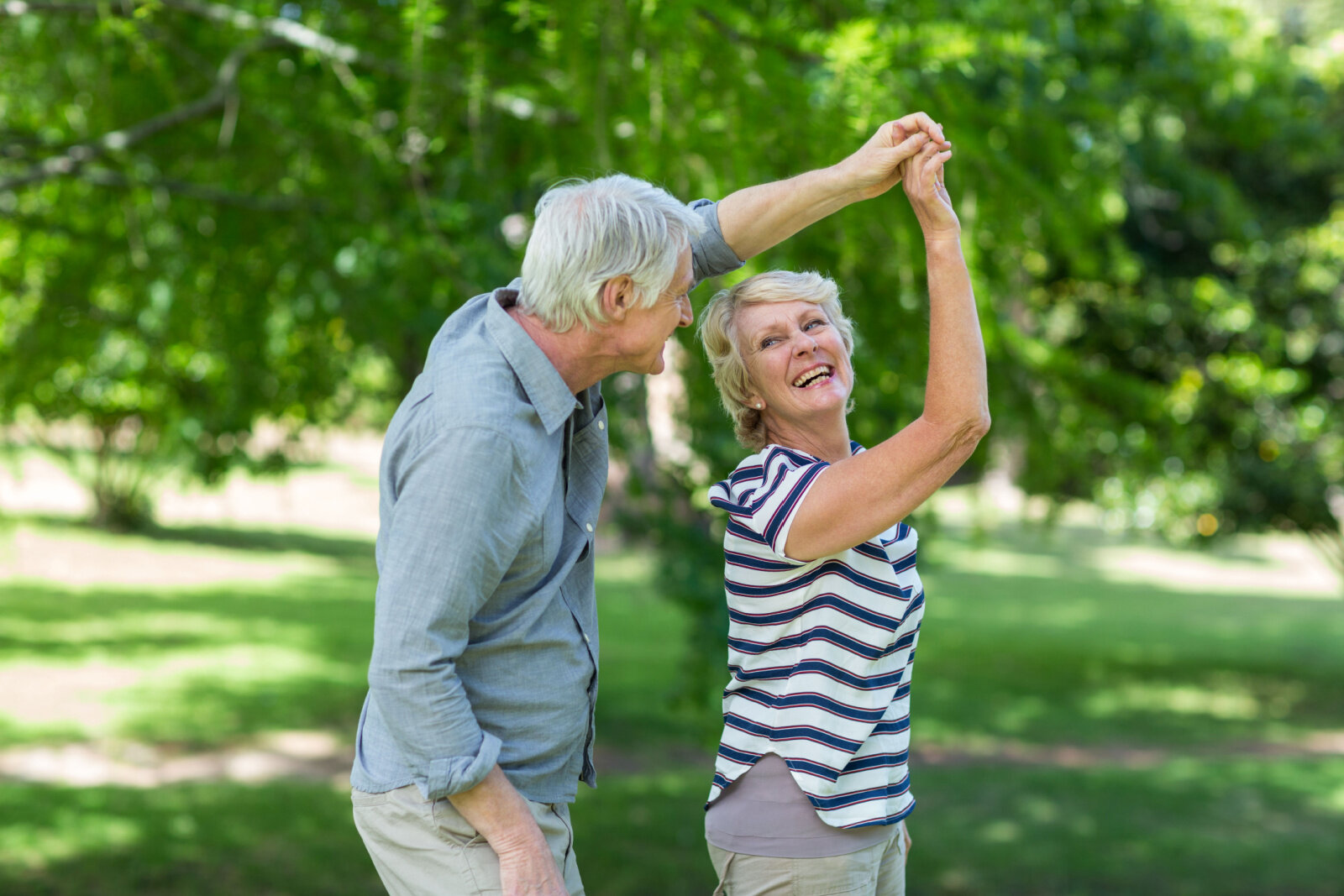 Senior couple dancing in park.