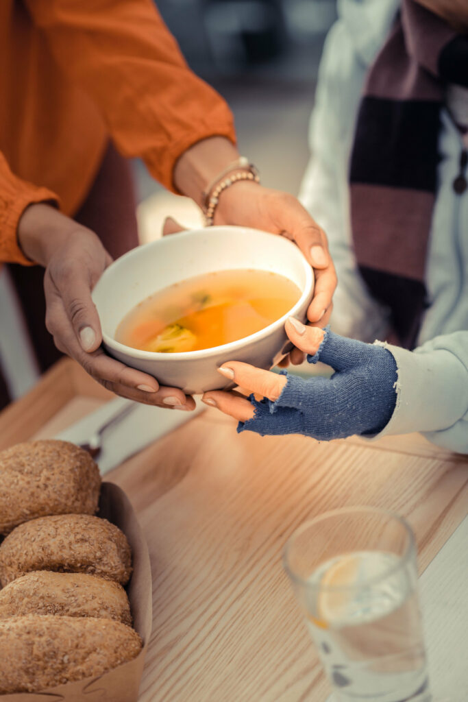 Woman hands holding bowl of chicken bouillon.