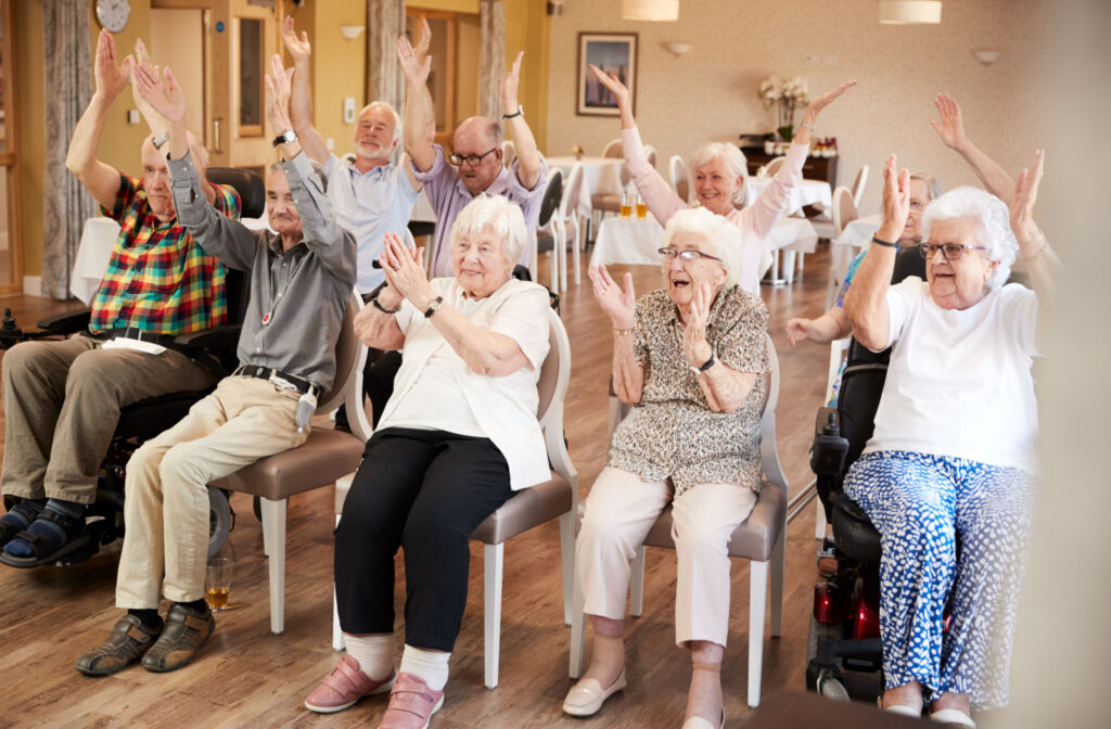 A group of seniors in a senior living community sitting and exercising together.
