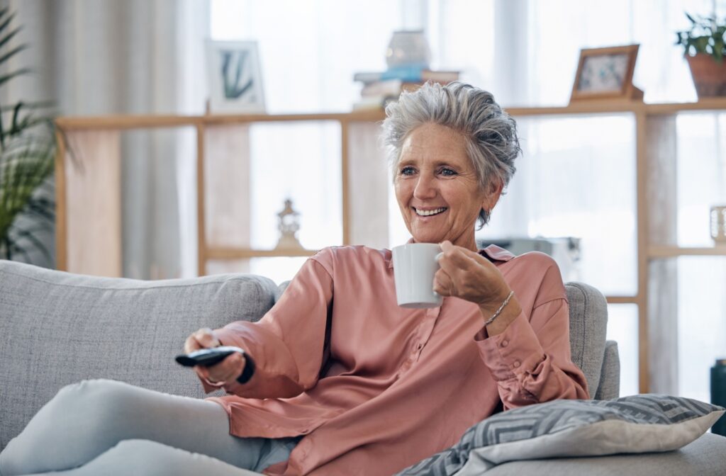 A happy older adult woman lounging in her living room.