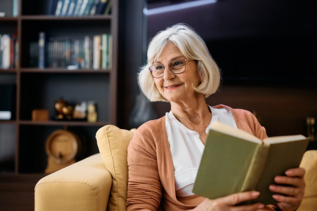 Older woman sitting reading a book.