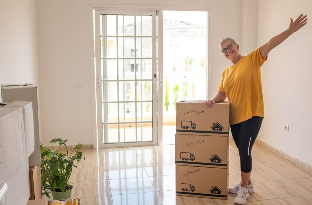 Happy senior leans against their final third moving boxes.