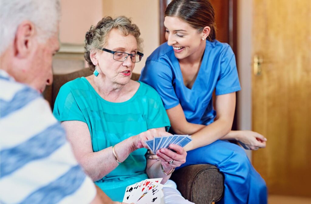 A nurse sits with a senior resident, chatting about their card game.