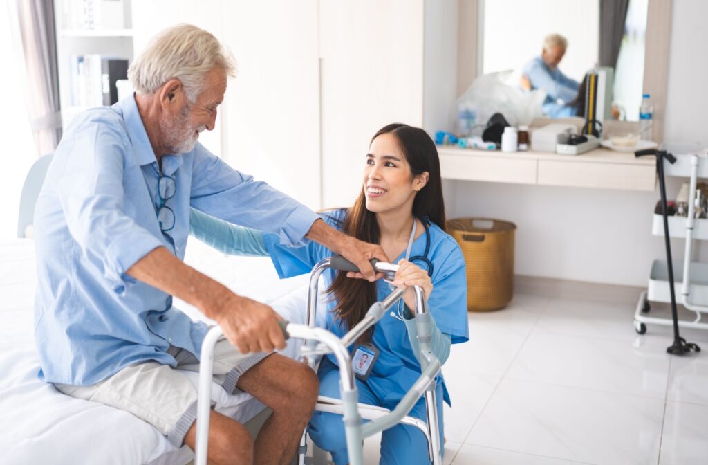 Senior with a walking aid having a seat while speaking with a caregiver in a bright assisted living facility.