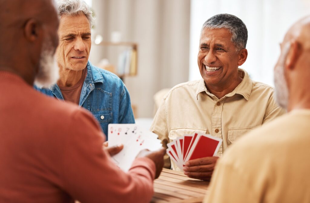 Group of senior men sitting at a table laughing and playing a card game.