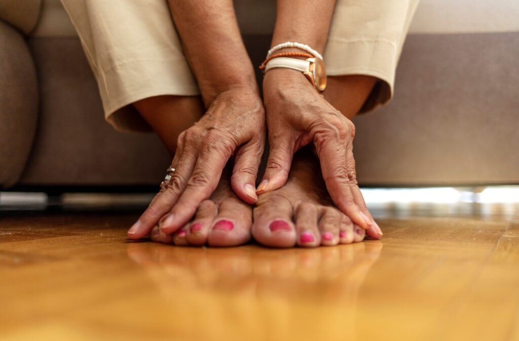 A senior sitting at the edge of their couch, gently rubbing their swollen ankles in discomfort.