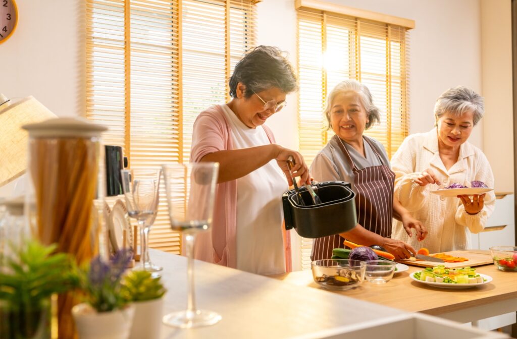 A group of seniors happily cooking a meal together in the kitchen of a senior living community, enjoying each other's company.