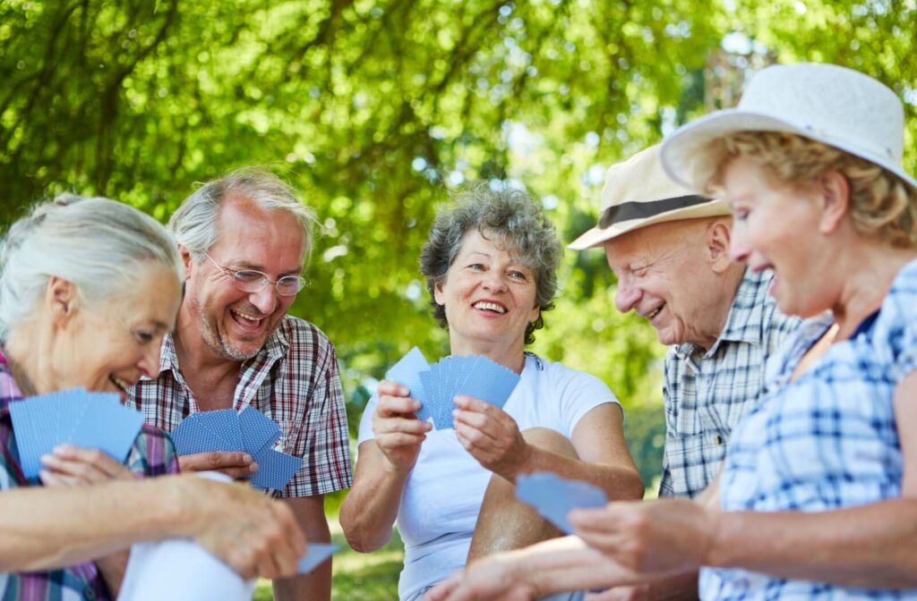 A group of seniors take an indoor card game outdoors to better enjoy the fresh summer air